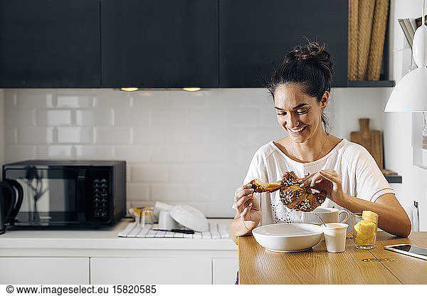Happy young woman having breakfast in kitchen
