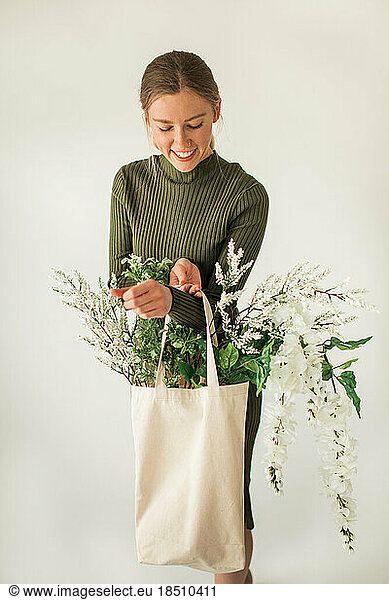 Happy Young Woman Holding Cloth Bag of White and Green Flowers