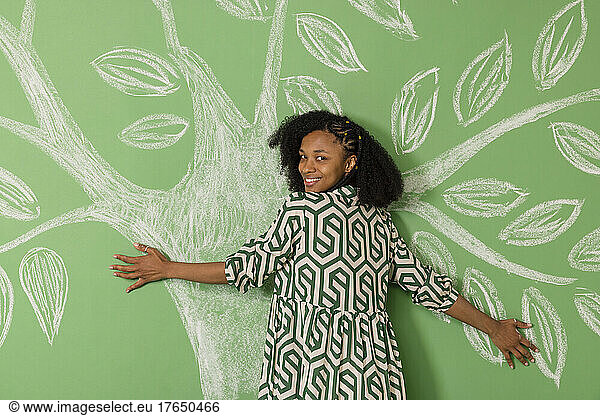 Happy young woman hugging palm branches in front of green background