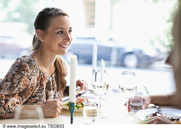 Happy young woman looking at friend at restaurant table
