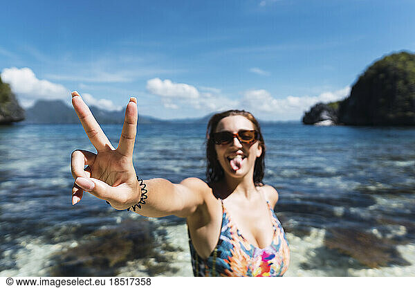 Happy young woman making peace sign in sea