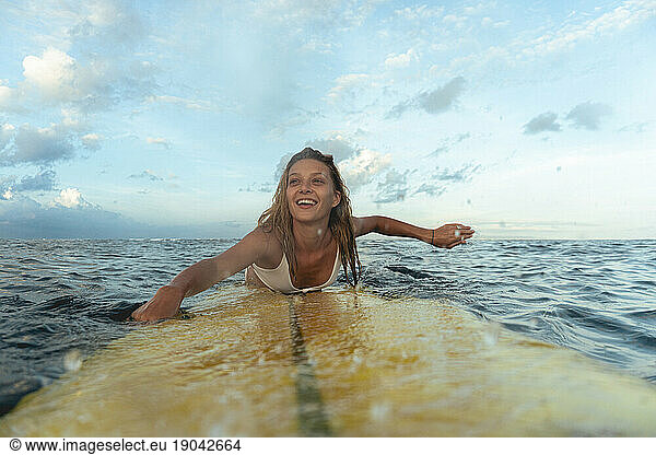 Happy young woman on a surfboard in the ocean  Bali.