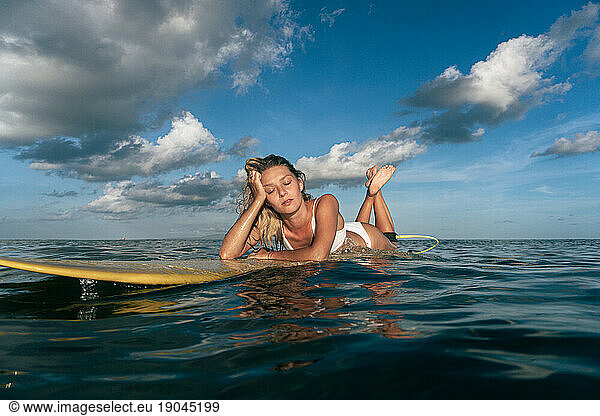 Happy young woman on a surfboard in the ocean  Bali.