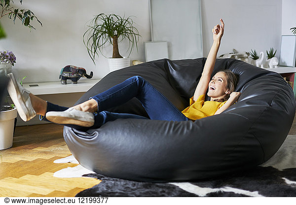 Happy young woman relaxing at home in beanbag