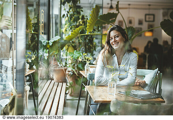 Happy young woman sitting at table in coffee shop
