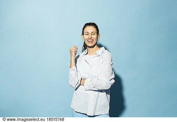 Happy young woman standing against blue background