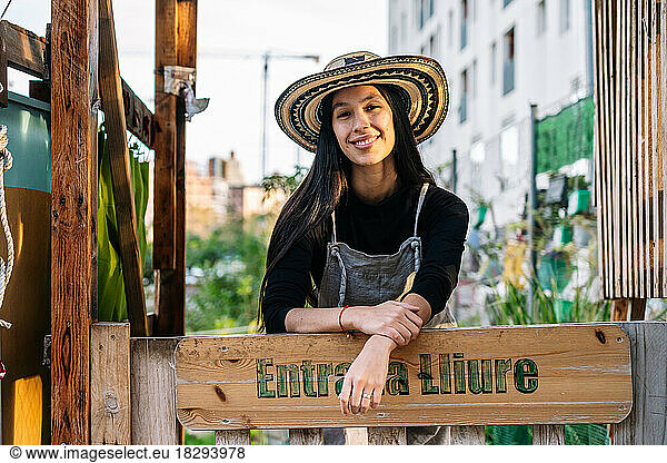 Happy young woman standing behind signboard in urban garden
