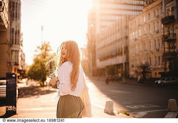Happy young woman standing on street in city during summer