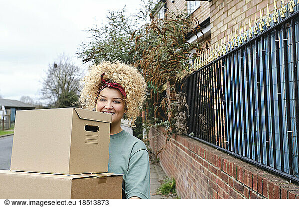 Happy young woman standing with boxes