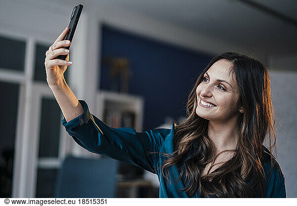 Happy young woman taking selfie at home