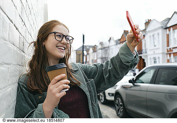 Happy young woman taking selfie through smart phone