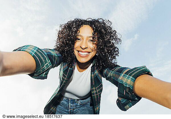 Happy young woman taking selfie under sky