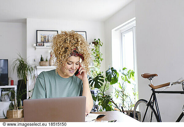 Happy young woman talking on smart phone at home