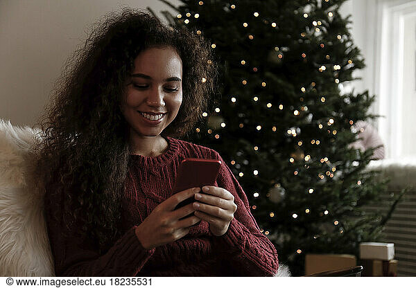 Happy young woman using smart phone at home
