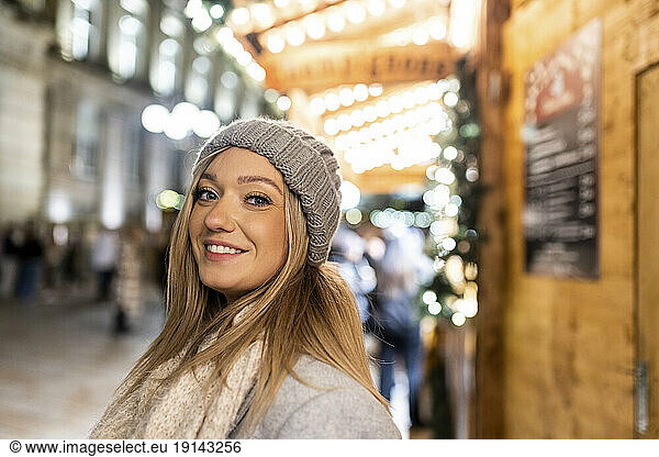 Happy young woman wearing knit hat at Christmas market