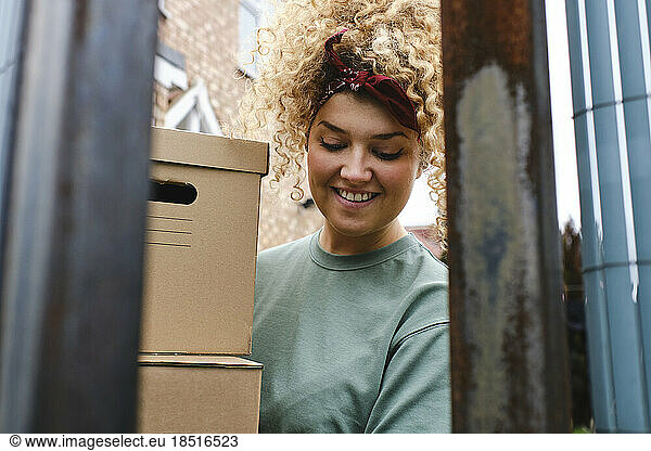 Happy young woman with curly hair delivering packages