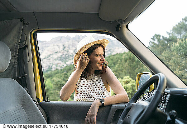 Happy young woman with hand in hair seen through van window