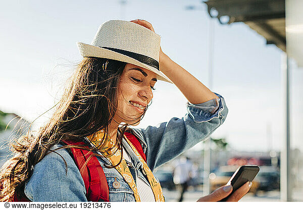 Happy young woman with hat using mobile phone
