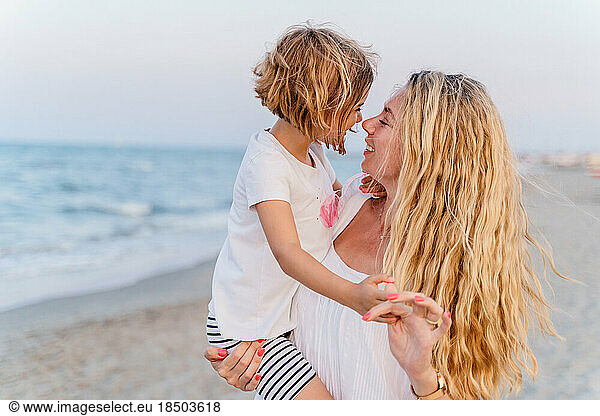 Happy young woman with her daughter hugging on the beach