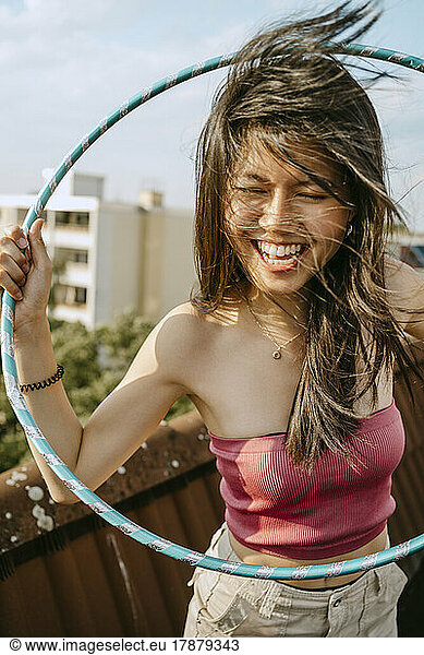 Happy young woman with hoola hoop enjoying on rooftop