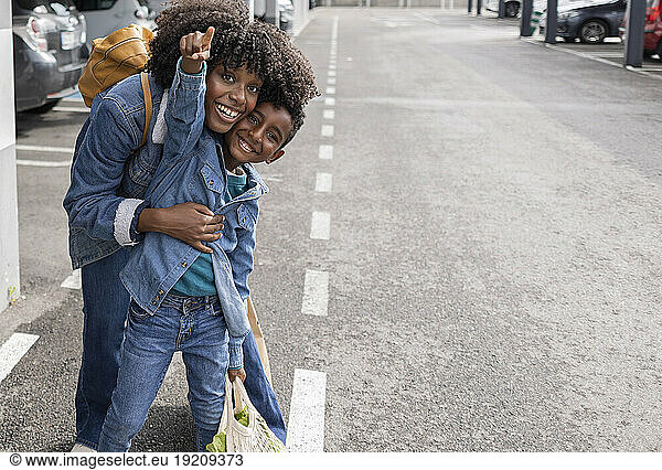 Happy young woman with son gesturing on road