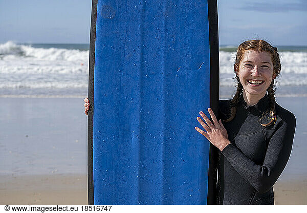 Happy young woman with surfboard at beach
