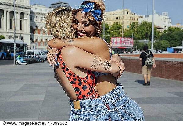 Happy young women hugging each other on footpath