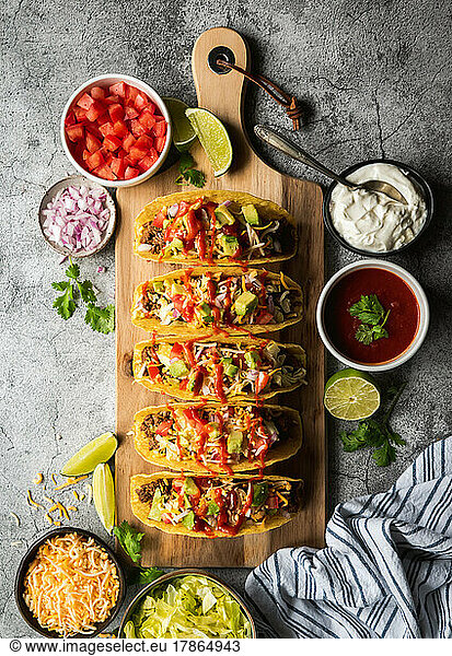 Hard shell tacos on wooden board with beef  lettuce  tomatoes  cheese.