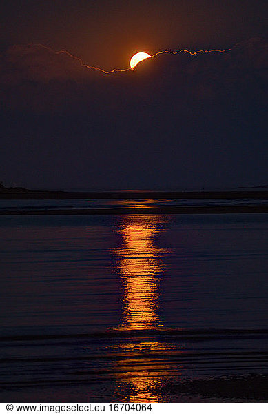 Harvest moon rises over clouds creating highlights on Atlantic waters