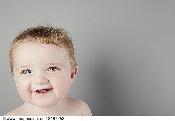 Head and shoulder studio portrait of smiling baby girl
