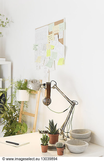 Headphones on desk lamp by houseplants on desk in creative office