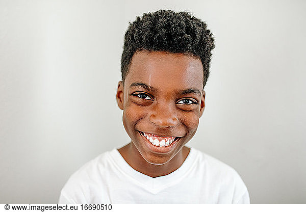 Headshot of sweet smiling black preteen boy wearing white t-shirt