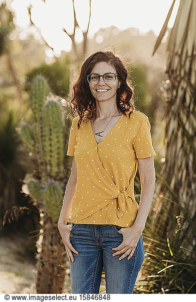 Headshot of young mother wearing glasses in backlight cactus garden