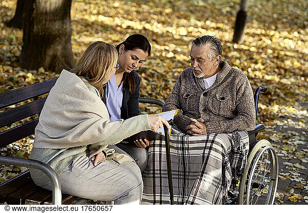 Healthcare worker discussing documents with senior couple at park