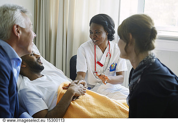 Healthcare worker encouraging patient and his family at hospital ward