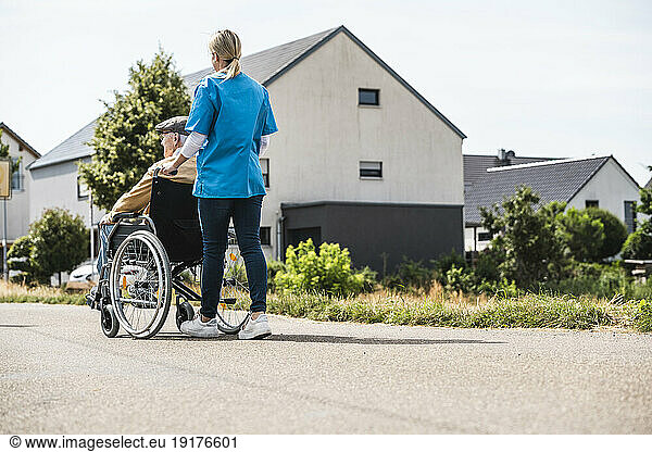 Healthcare worker pushing elderly man sitting in wheelchair