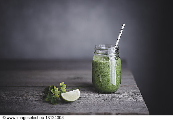 Healthy green smoothie in mason jar with lime on table