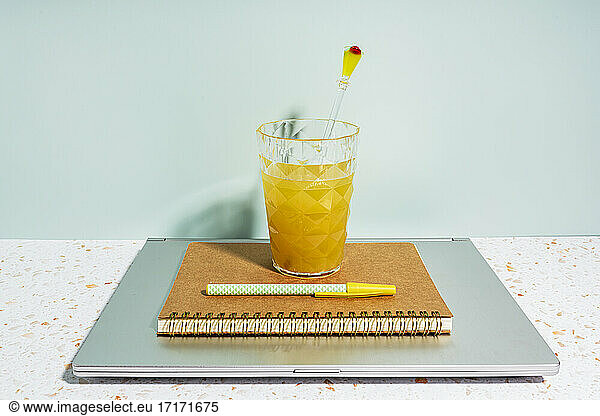 Healthy orange juice  book  pen and laptop on desk at home