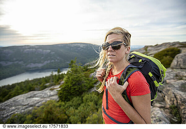 Healthy woman with sunglasses hikes on mountain summit  Maine