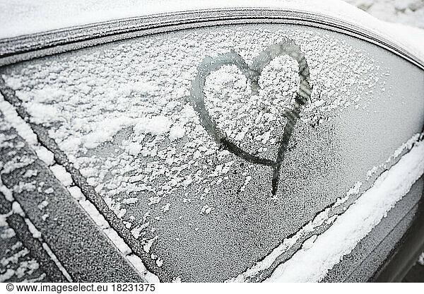 Heart shape on frosted car window in winter