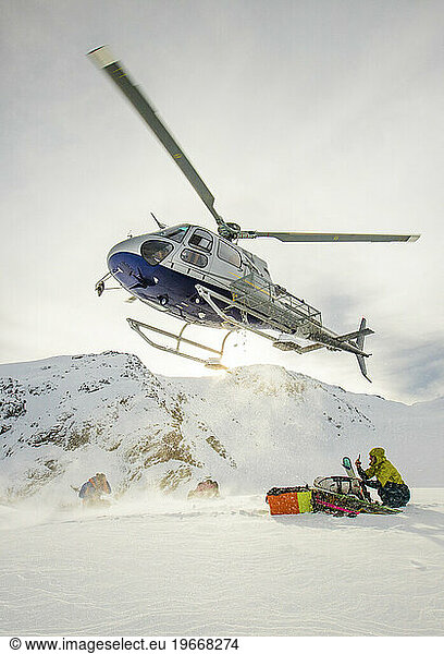 Helicopter landing to pick up skiers in the Coast Mountains