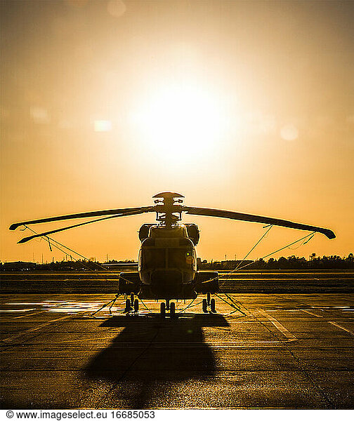 Helicopter on helipad while sun sets