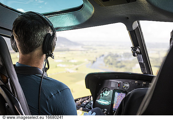 Helicopter pilot flying high above farmland below.