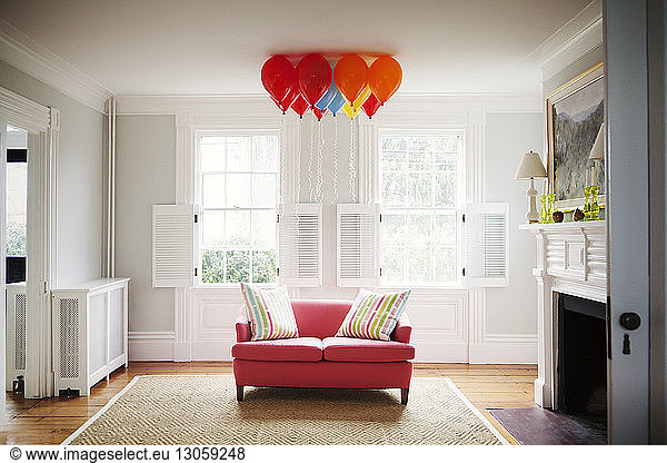 Helium balloons over sofa in living room at home