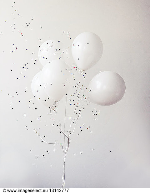 Helium balloons with confetti against wall