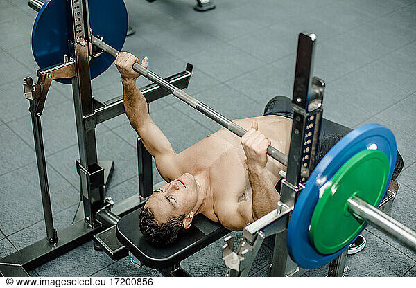 Hemdloser Athlet beim Bankdrücken im Fitnessstudio