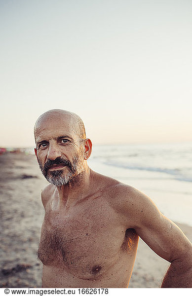 Hemdloser älterer Mann am Strand stehend