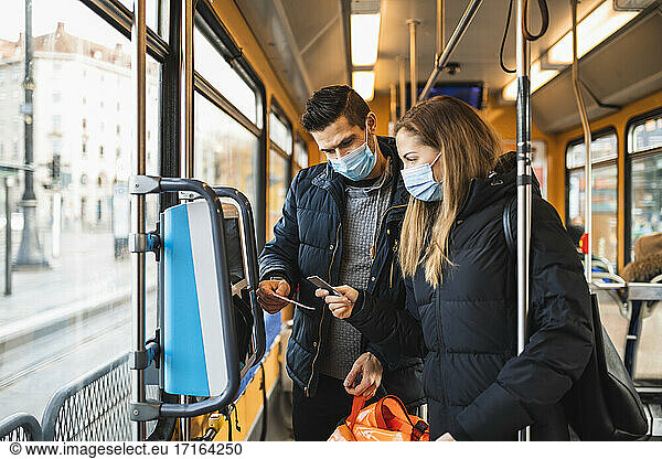 Heterosexual couple buying ticket in tram during pandemic