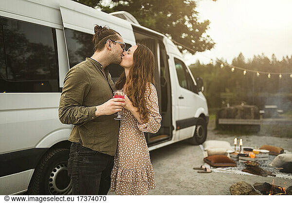 Heterosexual couple kissing by motor home during vacation