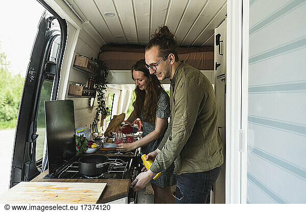 Heterosexual couple preparing food in camping van during vacation